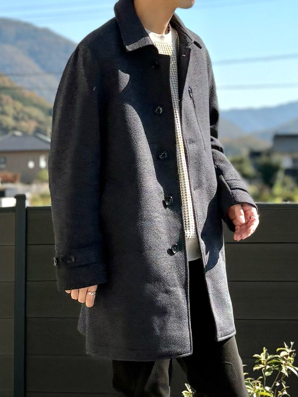 ブルー系のステンカラーコート、ベージュ系のスウェット、ブラック系のその他パンツを着用したメンズの秋コーディネートの3枚目の写真