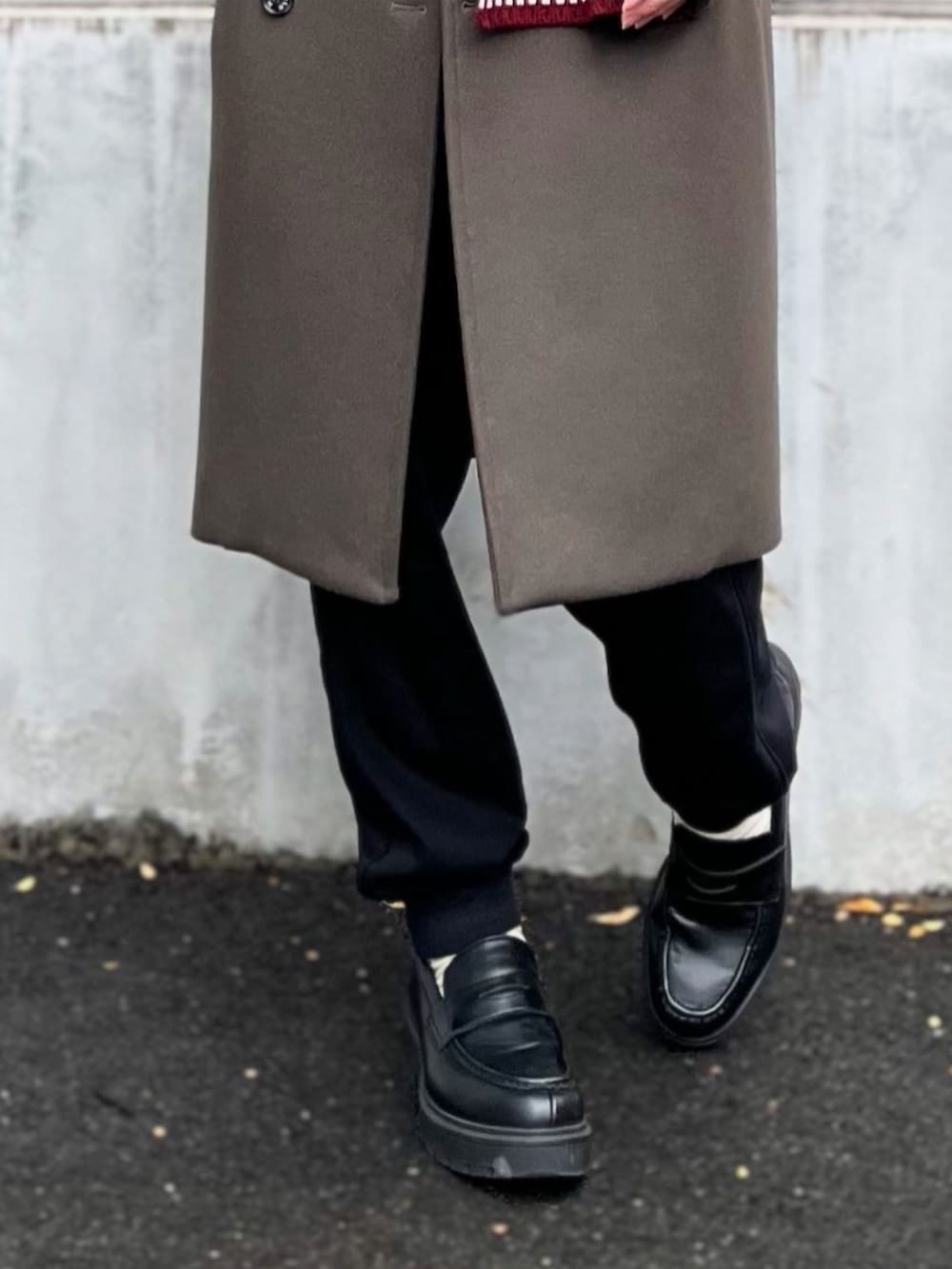 グリーン系のトレンチコート、ホワイト系のトップス、ブラック系のスウェットパンツを着用したメンズの冬コーディネートの4枚目の写真