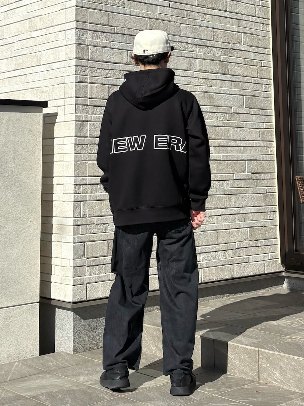 ブラック系のパーカー、ホワイト系のキャップ、グレー系のベルトを着用したメンズの冬コーディネートの2枚目の写真