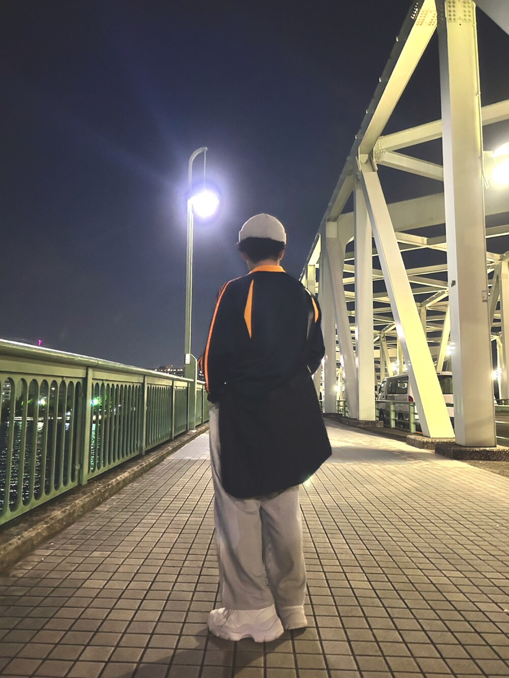 ブラック系のナイロンジャケット、ホワイト系のその他パンツ、ホワイト系のスニーカーを着用したメンズの春コーディネートの2枚目の写真