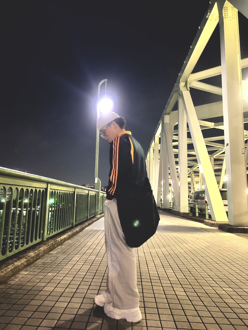 ブラック系のナイロンジャケット、ホワイト系のその他パンツ、ホワイト系のスニーカーを着用したメンズの春コーディネートの3枚目の写真