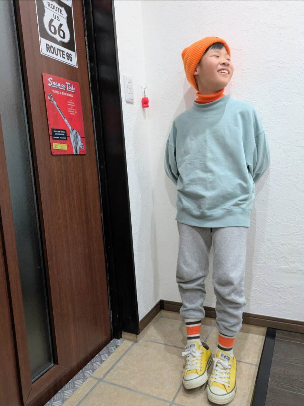 グレー系のスウェットパンツ、ブルー系のTシャツ/カットソー、オレンジ系のニット/セーターを着用したキッズの冬コーディネートの4枚目の写真