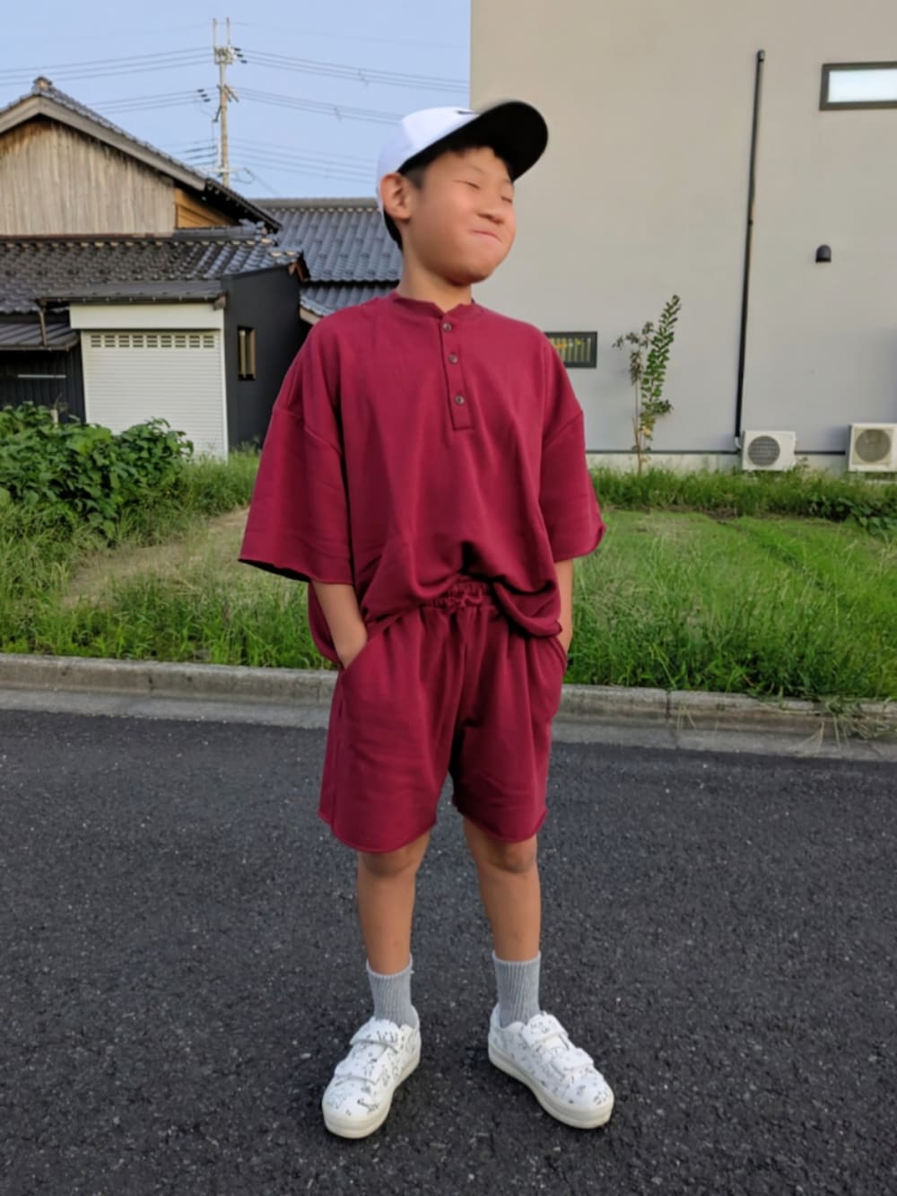 レッド系のセットアップ、ホワイト系のスニーカー、ホワイト系のキャップを着用したキッズの秋コーディネートの3枚目の写真