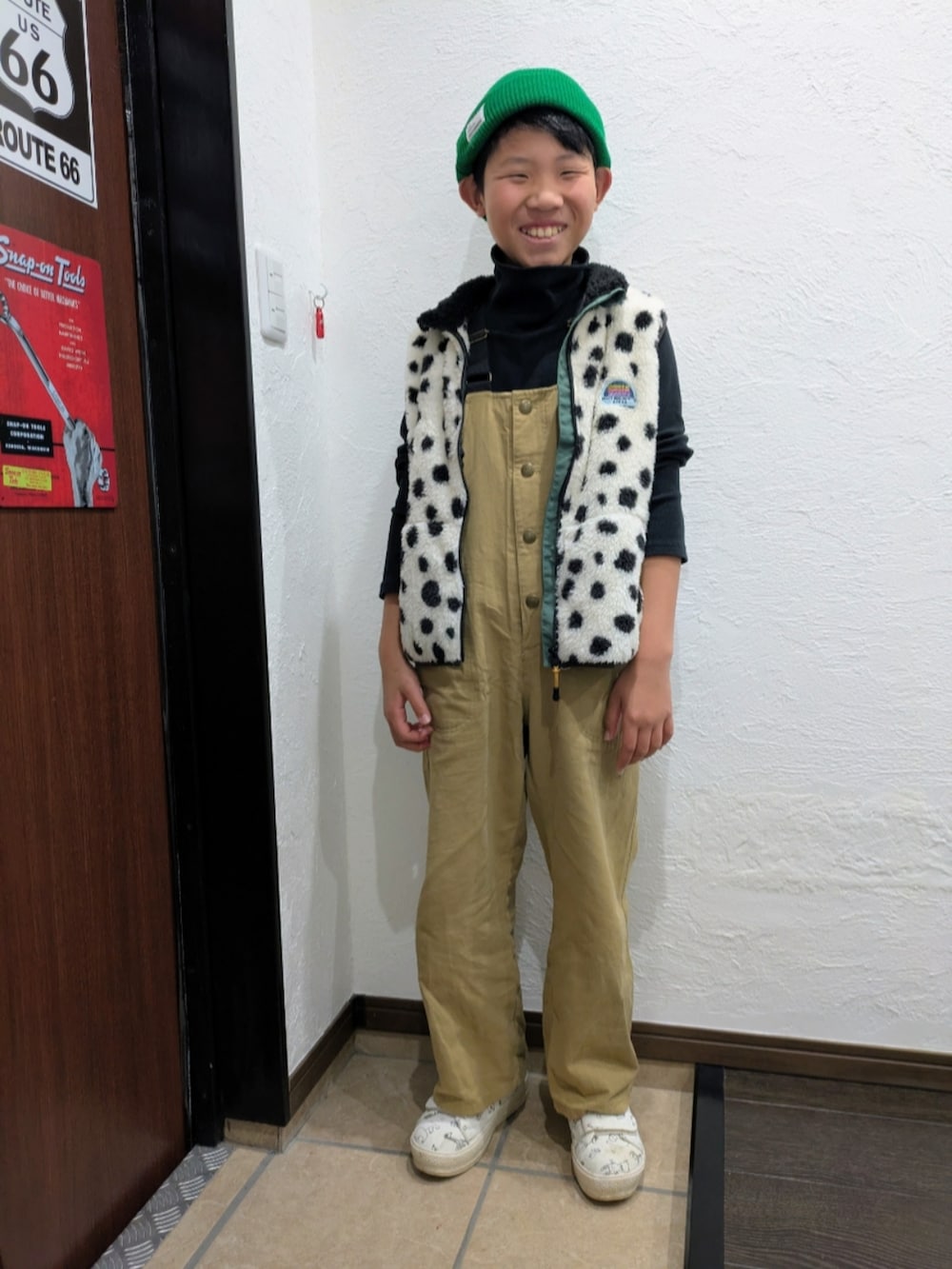 ベージュ系のサロペット/オーバーオール、ホワイト系のベスト、ブラック系のTシャツ/カットソーを着用したキッズの秋コーディネートの2枚目の写真