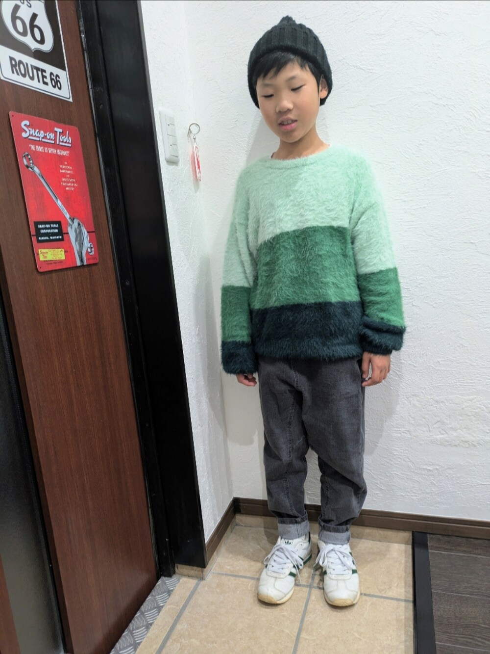 グレー系のデニムパンツ、グリーン系のニット/セーター、ホワイト系のスニーカーを着用したキッズの冬コーディネートの2枚目の写真