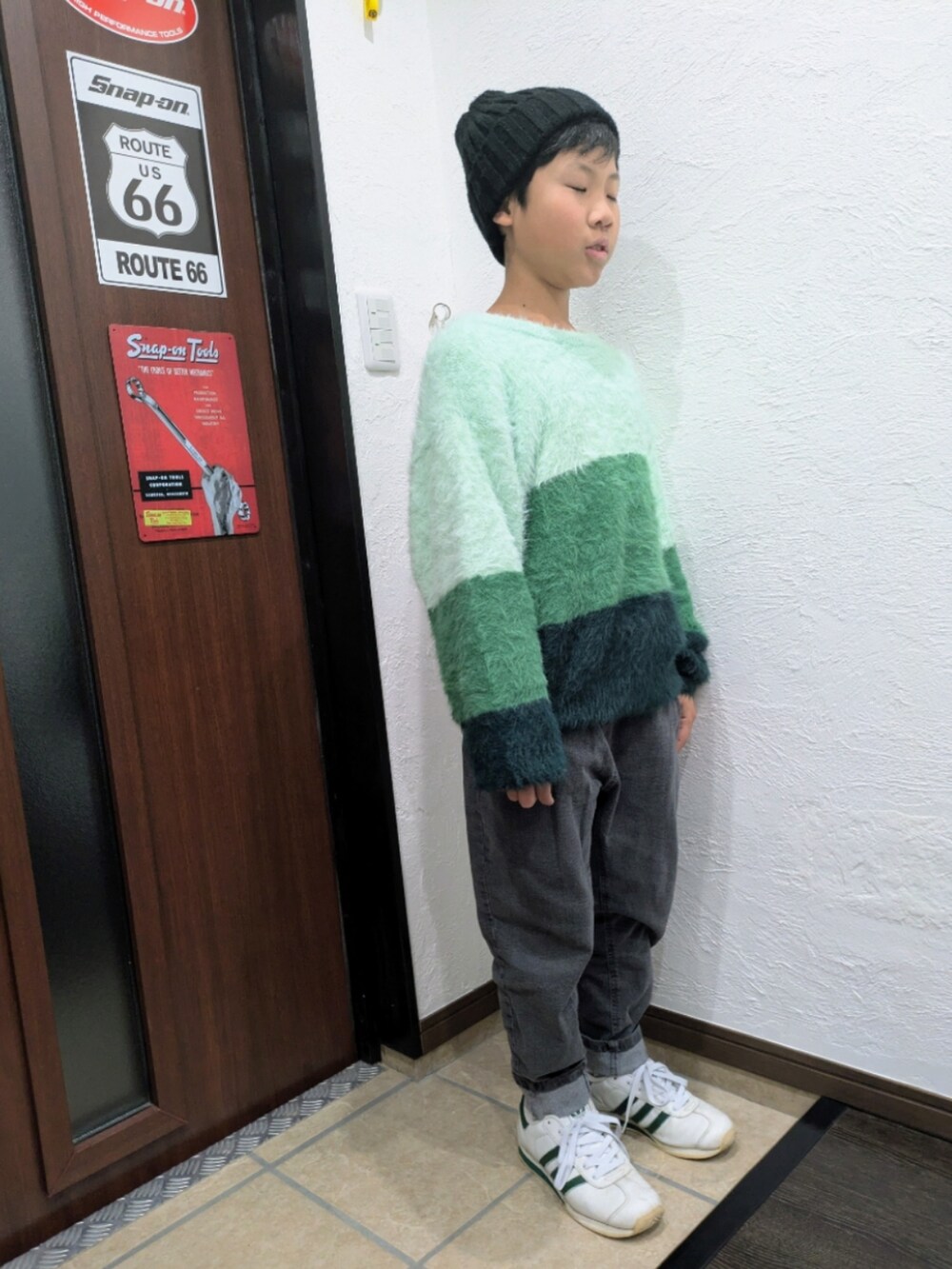 グレー系のデニムパンツ、グリーン系のニット/セーター、ホワイト系のスニーカーを着用したキッズの冬コーディネートの3枚目の写真