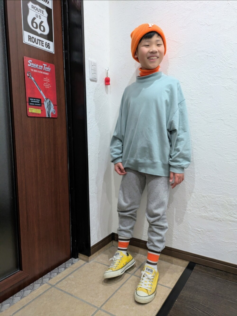 グレー系のスウェットパンツ、ブルー系のTシャツ/カットソー、オレンジ系のニット/セーターを着用したキッズの冬コーディネートの2枚目の写真