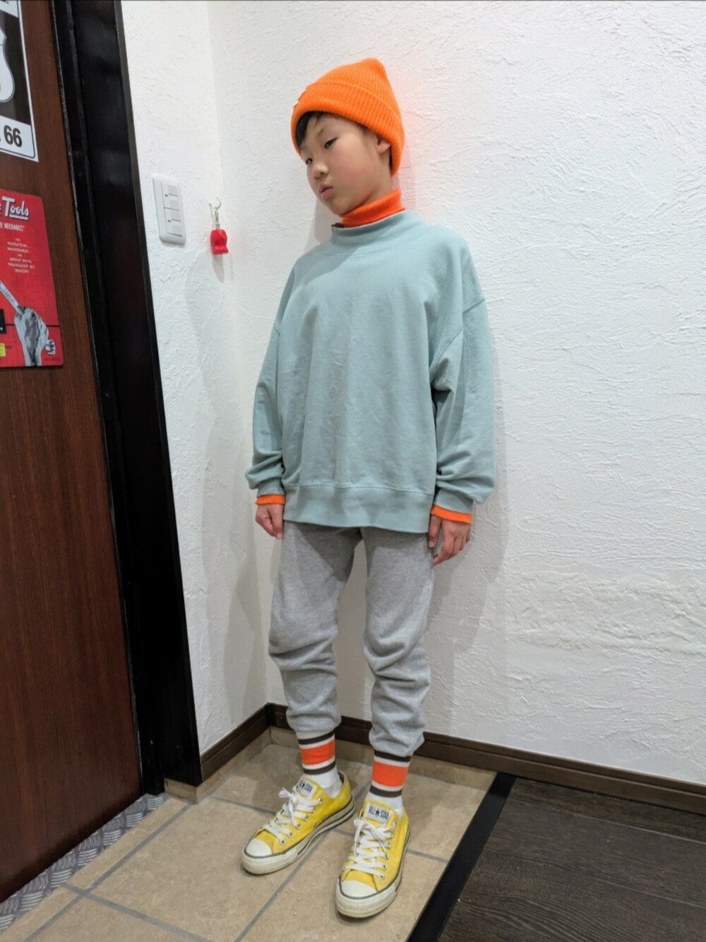 グレー系のスウェットパンツ、ブルー系のTシャツ/カットソー、オレンジ系のニット/セーターを着用したキッズの冬コーディネートの3枚目の写真