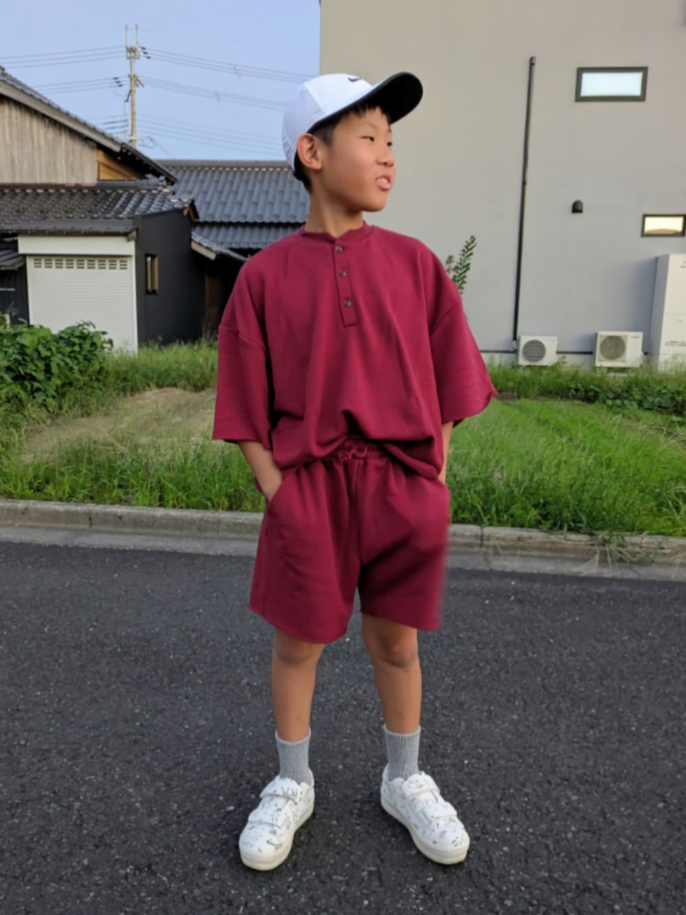 レッド系のセットアップ、ホワイト系のスニーカー、ホワイト系のキャップを着用したキッズの秋コーディネートの2枚目の写真