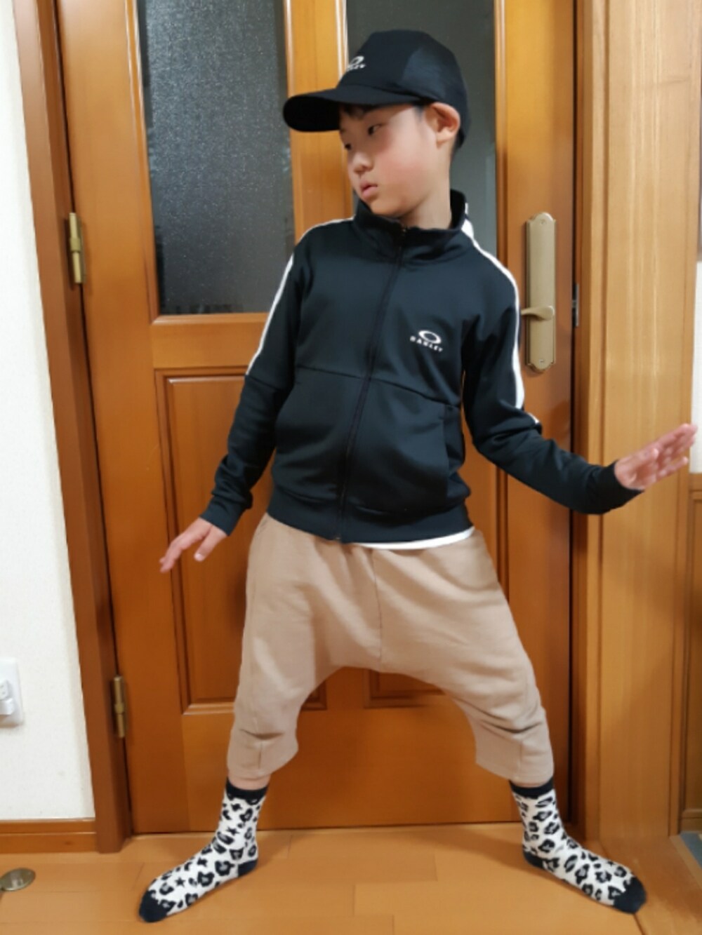 ベージュ系のパンツ、ブラック系のトップス、ブラック系のキャップを着用したキッズの春コーディネートの2枚目の写真