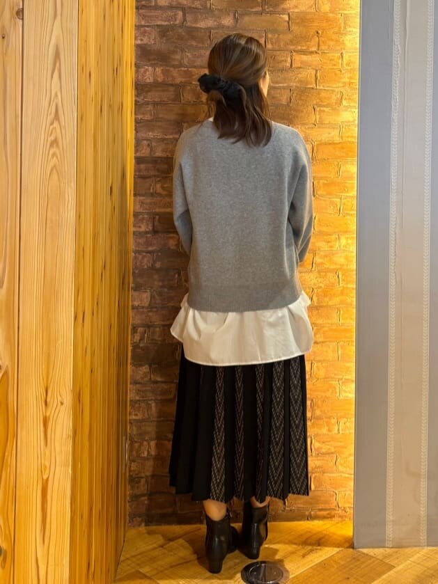 グレー系のニット/セーター、ホワイト系のチュニック、ブラック系のスカートを着用したレディースの秋コーディネートの2枚目の写真