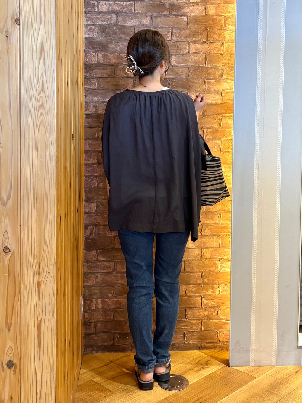 ブルー系のデニムパンツ、グレー系のサンダル、ブラック系のトートバッグを着用したレディースの夏コーディネートの3枚目の写真