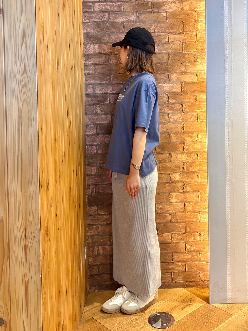 ブルー系のTシャツ/カットソー、グレー系のスカート、ホワイト系のスニーカーを着用したレディースの夏コーディネートの2枚目の写真