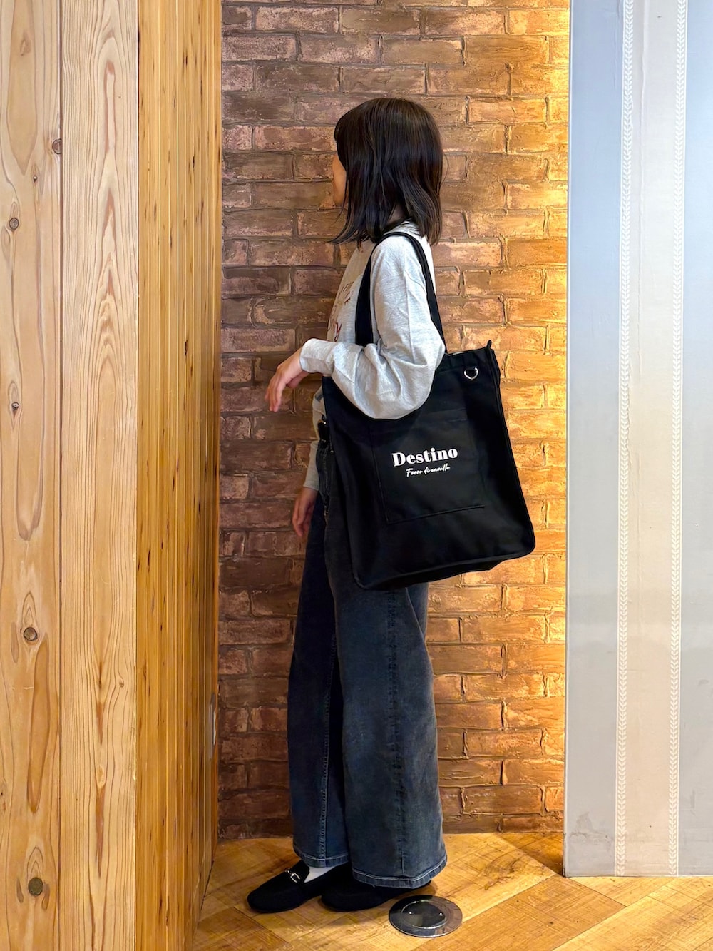グレー系のTシャツ/カットソー、ブルー系のデニムパンツ、ブラック系のその他シューズを着用したレディースの秋コーディネートの2枚目の写真