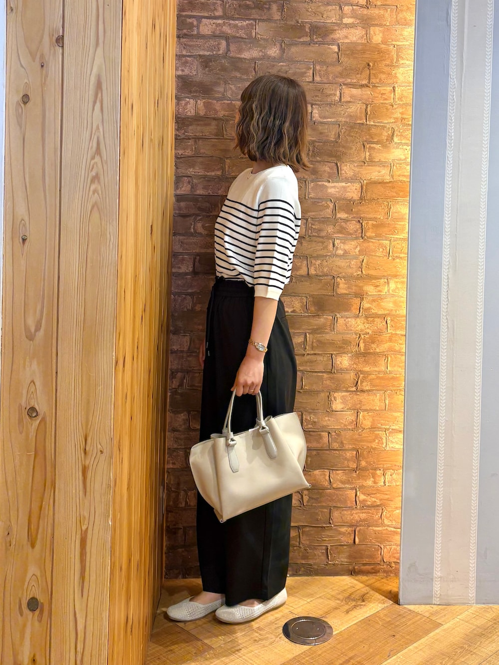 ホワイト系のニット/セーター、ゴールド系のパンプス、グレー系のトートバッグを着用したレディースの夏コーディネートの2枚目の写真