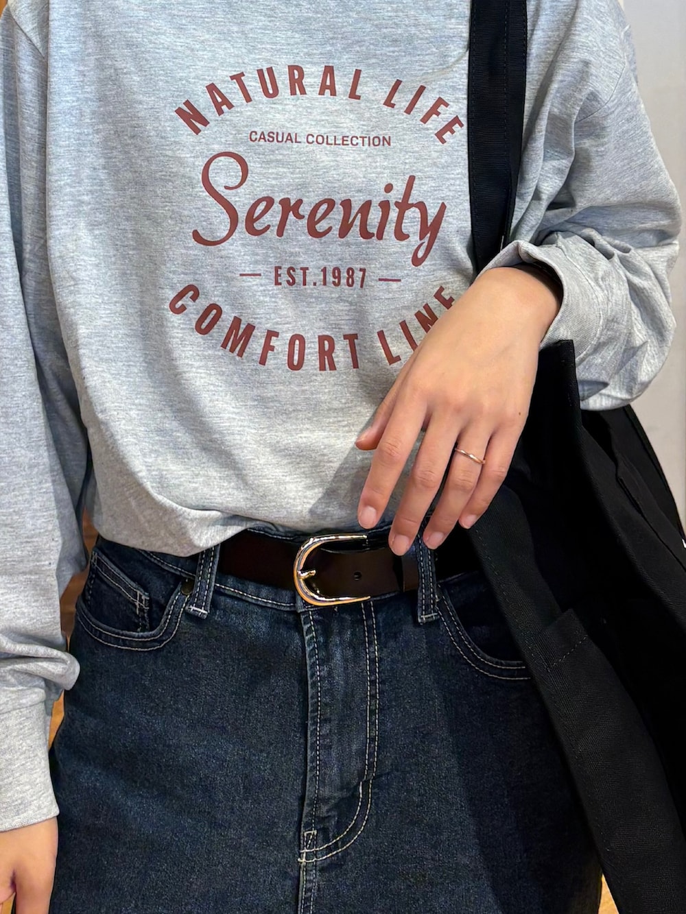 グレー系のTシャツ/カットソー、ブルー系のデニムパンツ、ブラック系のその他シューズを着用したレディースの秋コーディネートの4枚目の写真