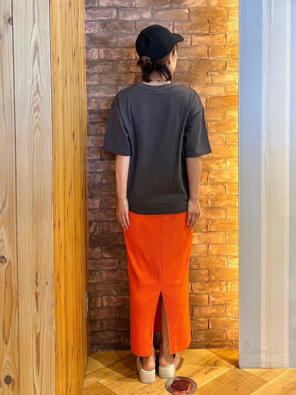 オレンジ系のスカート、ベージュ系のサンダル、ブラック系のキャップを着用したレディースの夏コーディネートの3枚目の写真