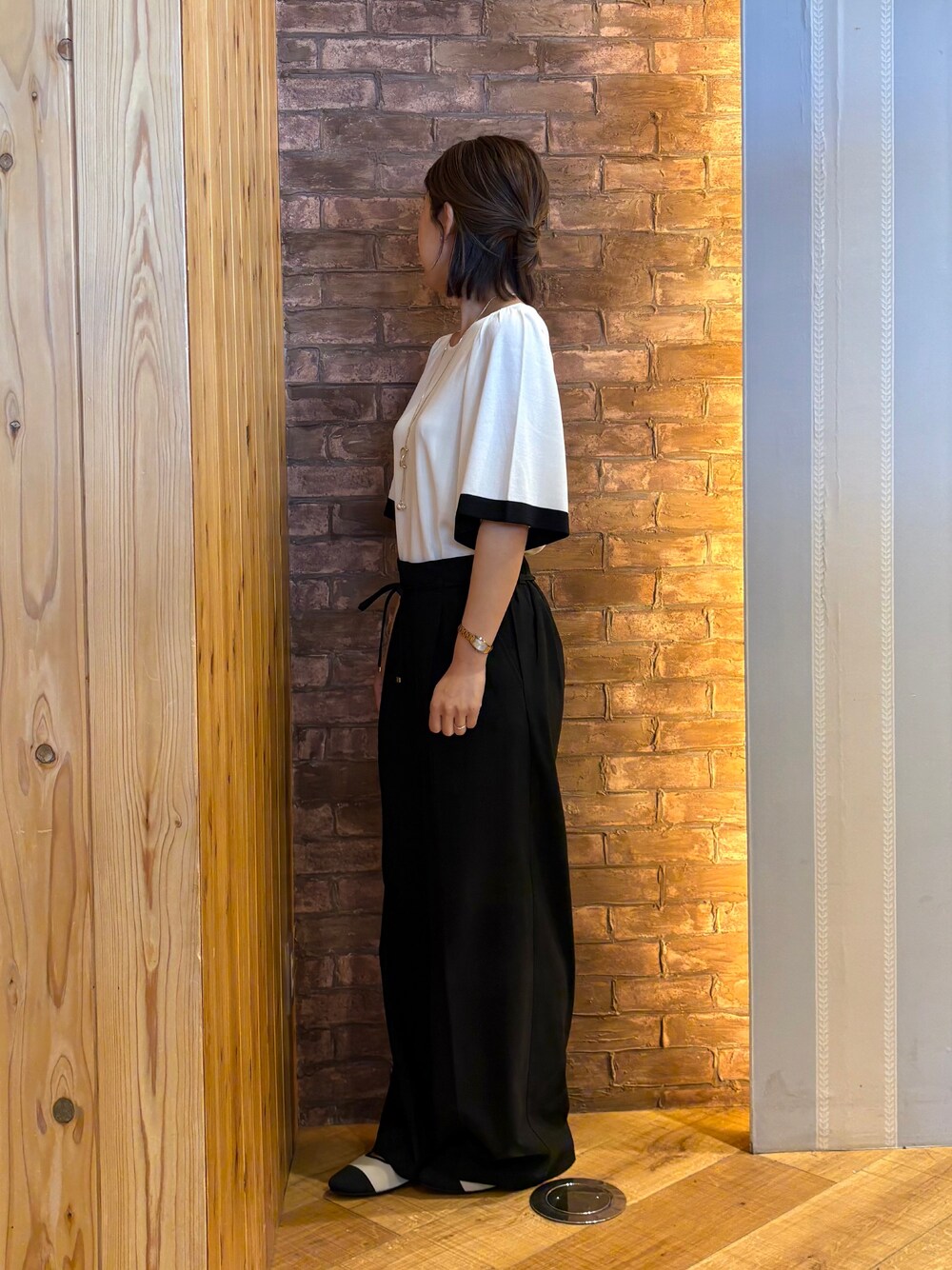 ブラック系のその他パンツ、ホワイト系のニット/セーター、ベージュ系のパンプスを着用したレディースの夏コーディネートの2枚目の写真