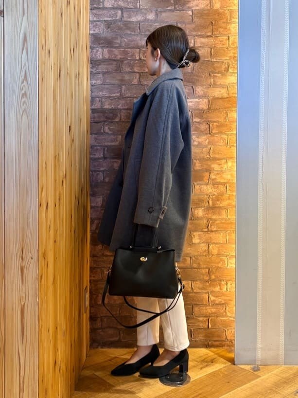 グレー系のチェスターコート、ブルー系のニット/セーター、ホワイト系のその他パンツを着用したレディースの冬コーディネートの2枚目の写真