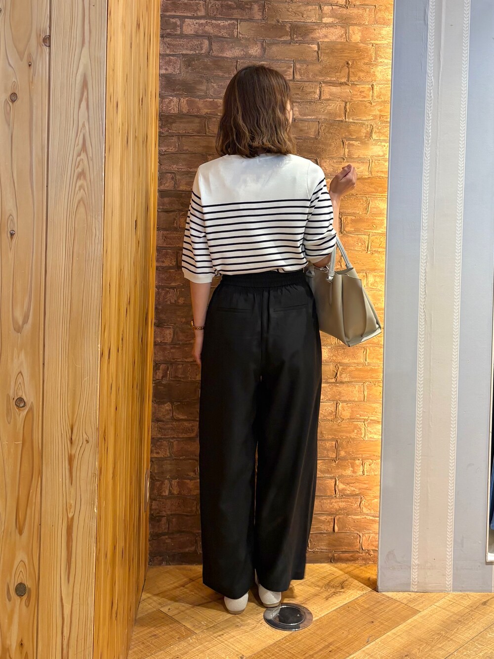 ホワイト系のニット/セーター、ゴールド系のパンプス、グレー系のトートバッグを着用したレディースの夏コーディネートの3枚目の写真