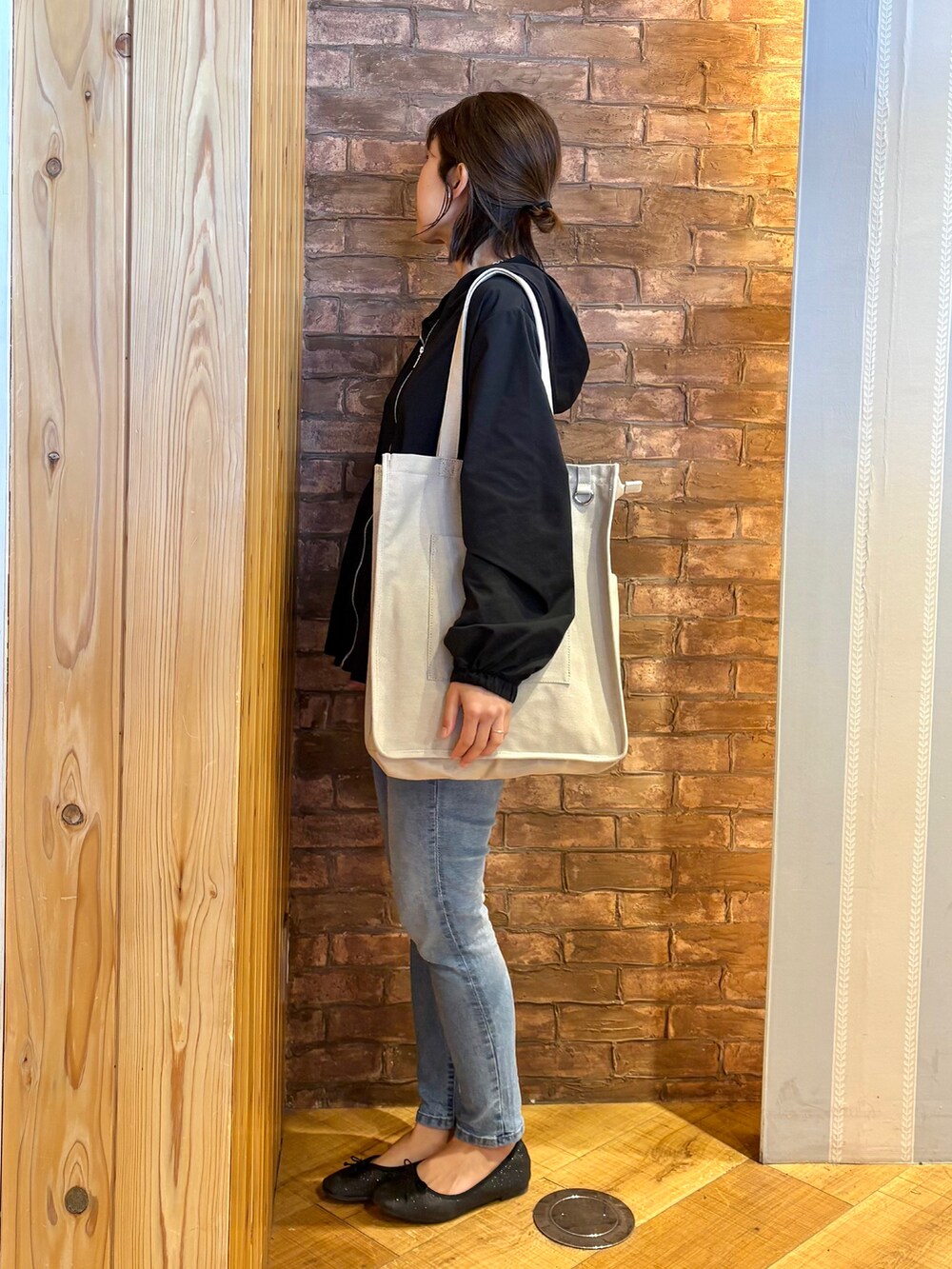 ブラック系のブルゾン、ブラック系のタンクトップ、ブルー系のデニムパンツを着用したレディースの春コーディネートの2枚目の写真