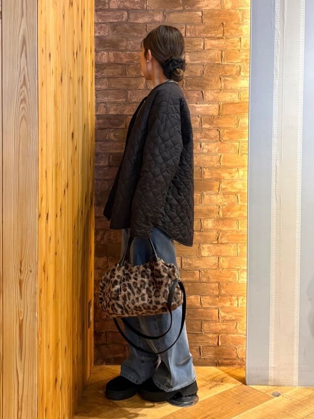 ブラック系のノーカラージャケット、ベージュ系のニット/セーター、ブルー系のデニムパンツを着用したレディースの冬コーディネートの2枚目の写真