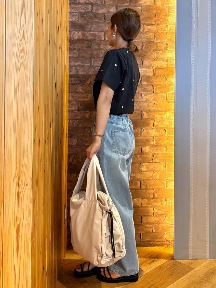 ブラック系のTシャツ/カットソー、ブルー系のデニムパンツ、ブラック系のサンダルを着用したレディースの春コーディネートの2枚目の写真