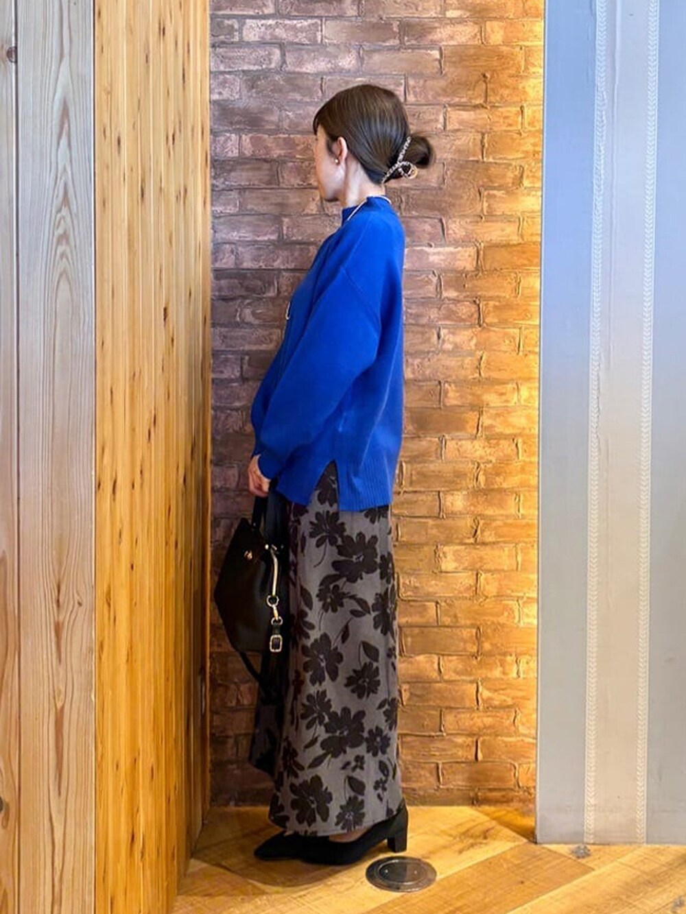 ブルー系のニット/セーター、グレー系のスカート、ブラック系のパンプスを着用したレディースの冬コーディネートの2枚目の写真