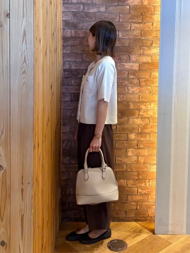 グレー系のトートバッグ、ブラック系のその他シューズ、ブラウン系のその他パンツを着用したレディースの春コーディネートの2枚目の写真