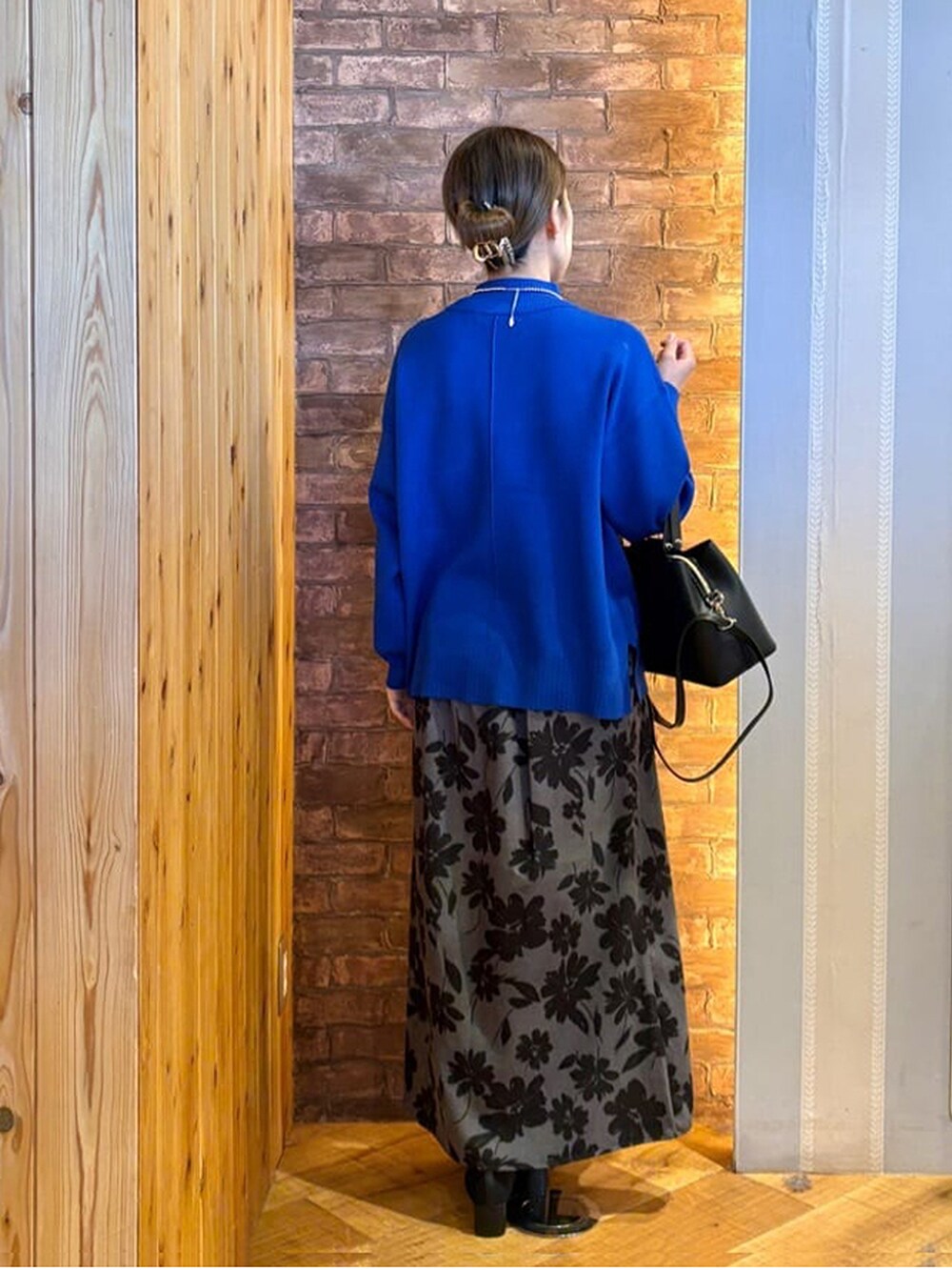 ブルー系のニット/セーター、グレー系のスカート、ブラック系のパンプスを着用したレディースの冬コーディネートの3枚目の写真