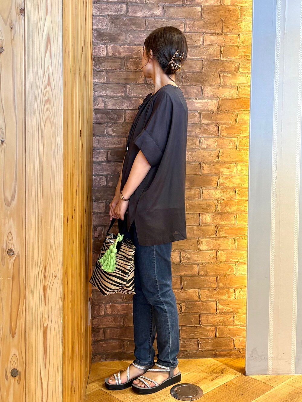 ブルー系のデニムパンツ、グレー系のサンダル、ブラック系のトートバッグを着用したレディースの夏コーディネートの2枚目の写真