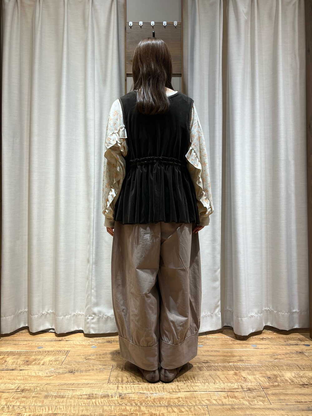 ベージュ系のパンツ、ブラウン系のベスト、イエロー系のトップスを着用したレディースの秋コーディネートの3枚目の写真