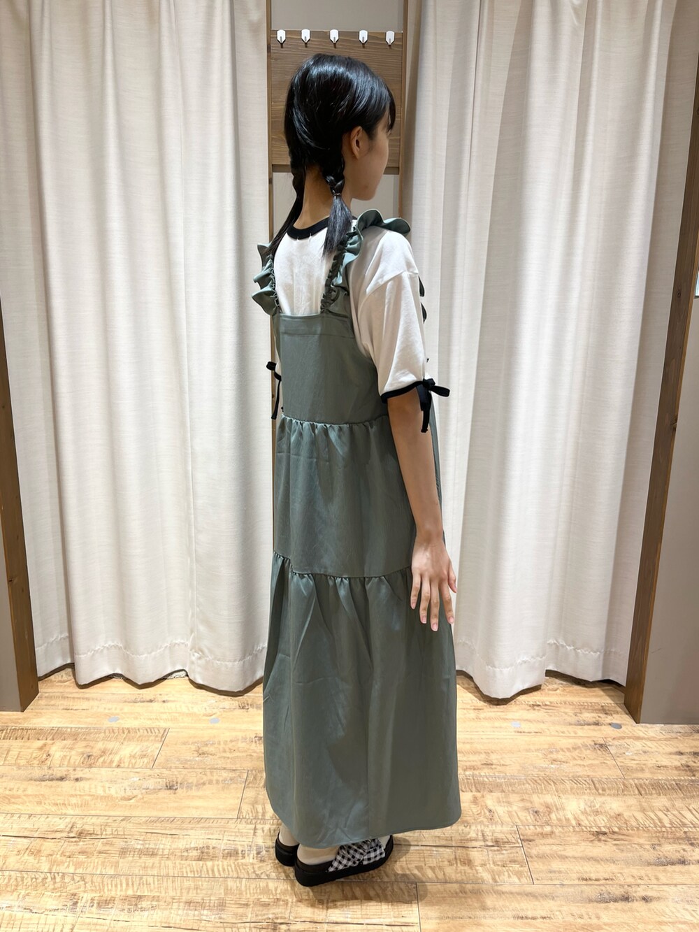 グリーン系のワンピース、ホワイト系のTシャツ/カットソー、ブラック系のサンダルを着用したレディースの夏コーディネートの2枚目の写真