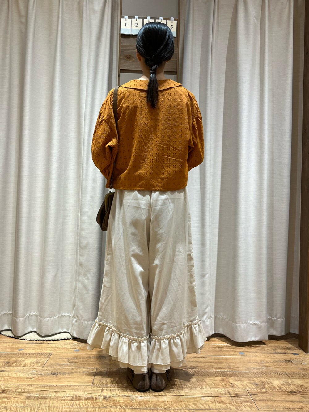 オレンジ系のシャツ/ブラウス、ブラウン系のバッグ、ブラウン系のシューズを着用したレディースの夏コーディネートの2枚目の写真