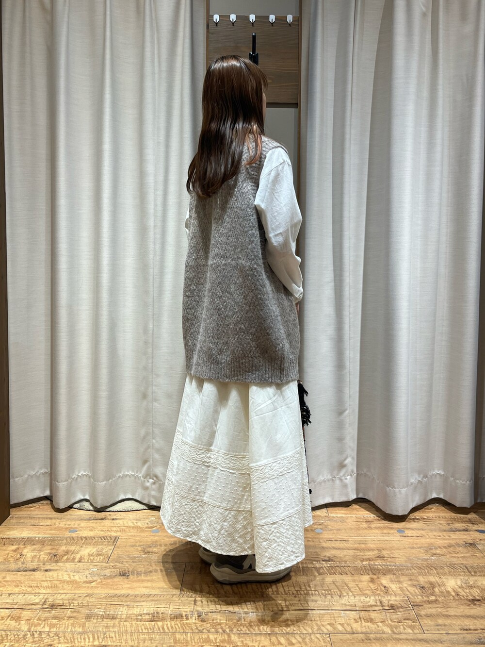 ベージュ系のベスト、ホワイト系のスカート、ブラック系のバッグを着用したレディースの冬コーディネートの2枚目の写真