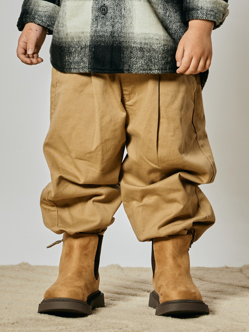 ベージュ系のチノパンツ、ブラック系のブルゾン、ベージュ系のブーツを着用したキッズの冬コーディネートの3枚目の写真