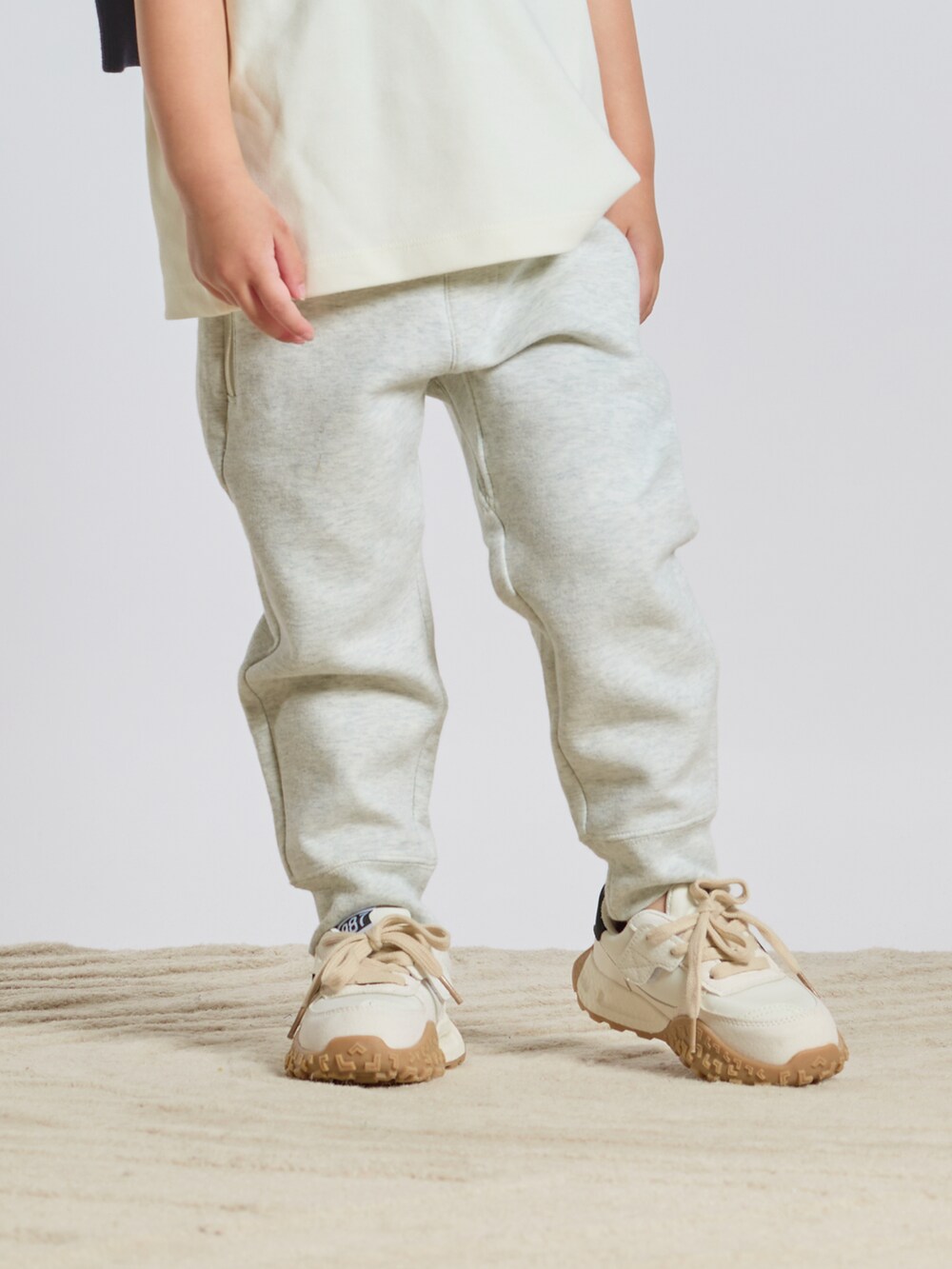 ホワイト系のTシャツ/カットソー、ブルー系のニット/セーター、ホワイト系のスウェットパンツを着用したキッズの秋コーディネートの3枚目の写真