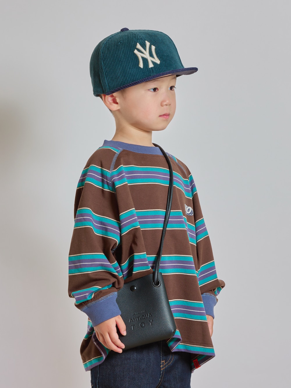 ブラウン系のTシャツ/カットソー、ブルー系のデニムパンツ、ブラック系のショルダーバッグを着用したキッズの秋コーディネートの3枚目の写真