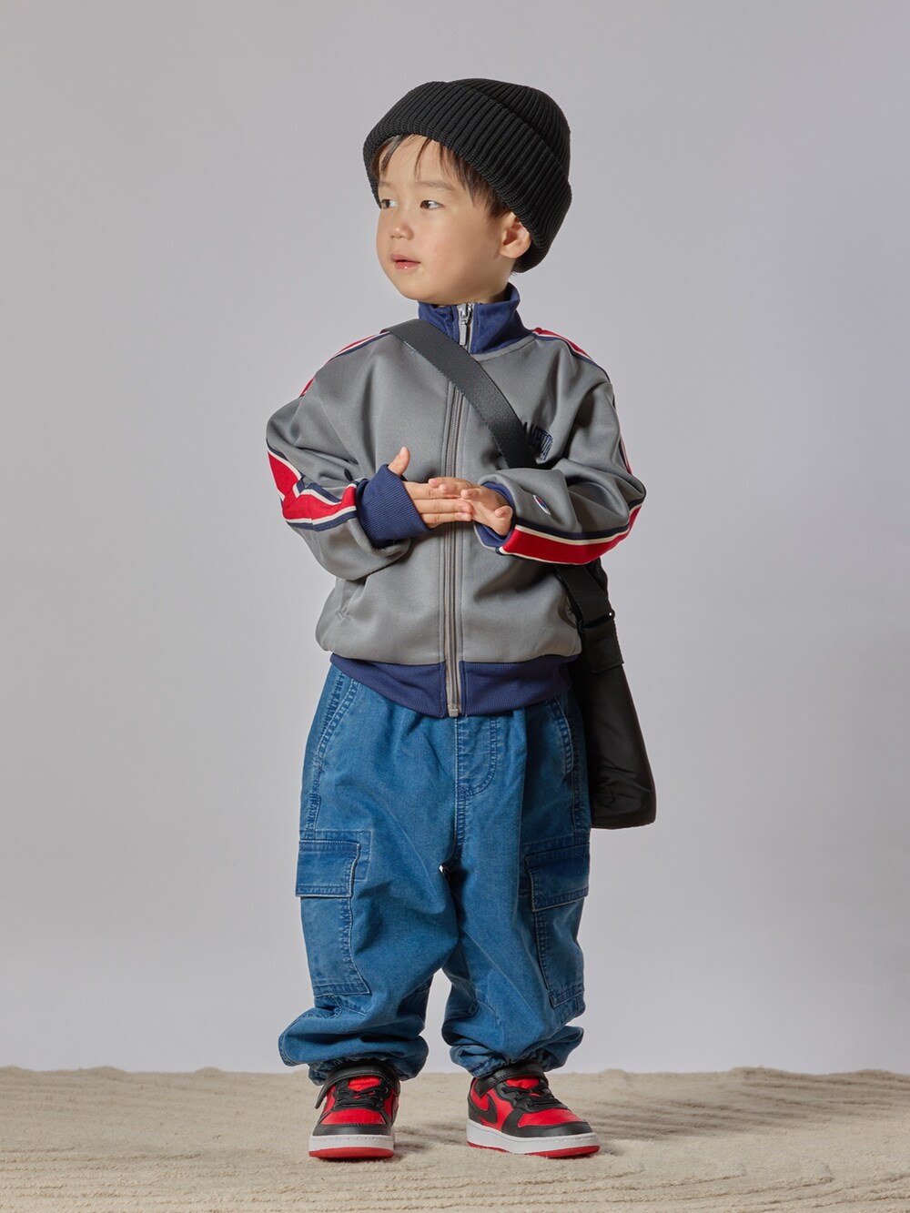 グレー系のブルゾン、ブルー系のカーゴパンツ、レッド系のスニーカーを着用したキッズの秋コーディネートの2枚目の写真