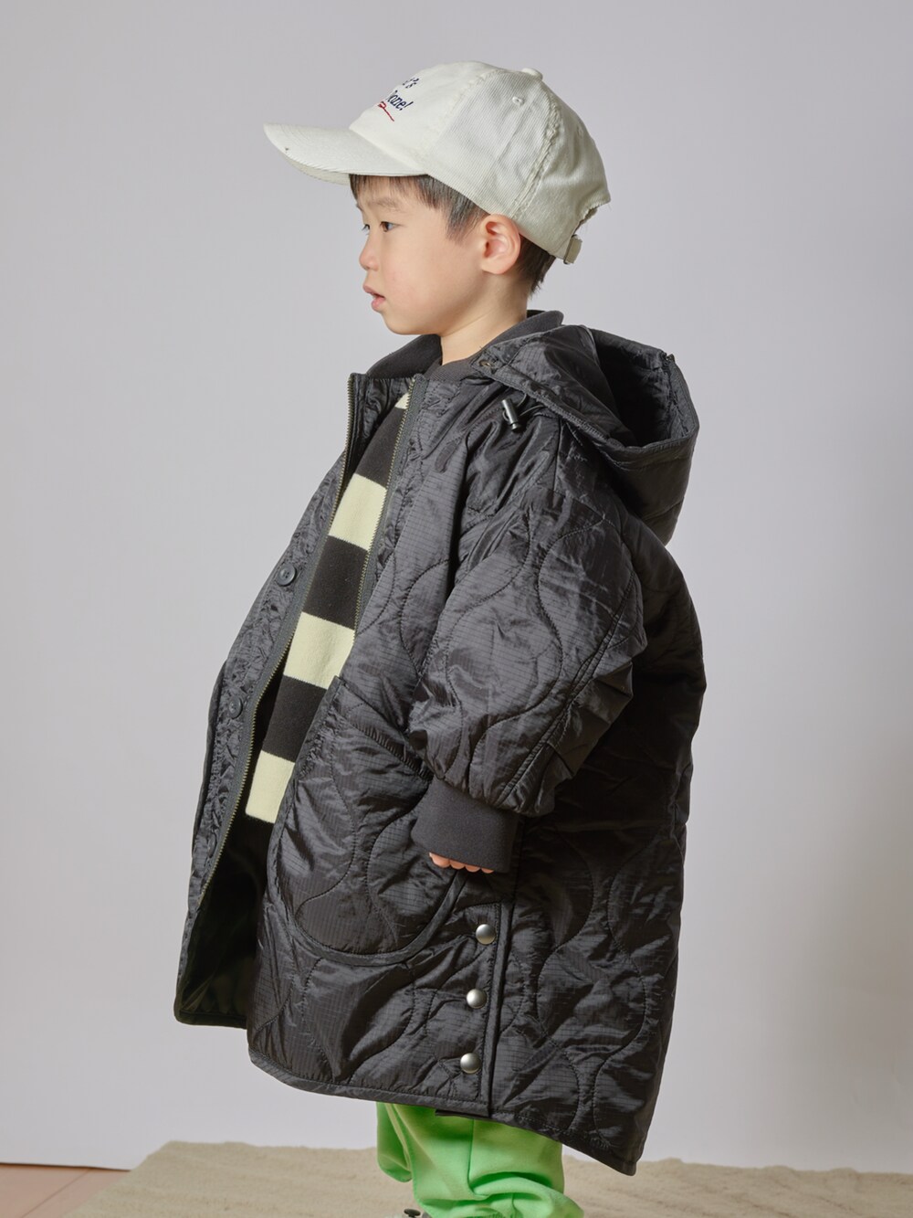 ブラック系のニット/セーター、ブラック系のダウンジャケット/コート、グリーン系のその他パンツを着用したキッズの冬コーディネートの2枚目の写真