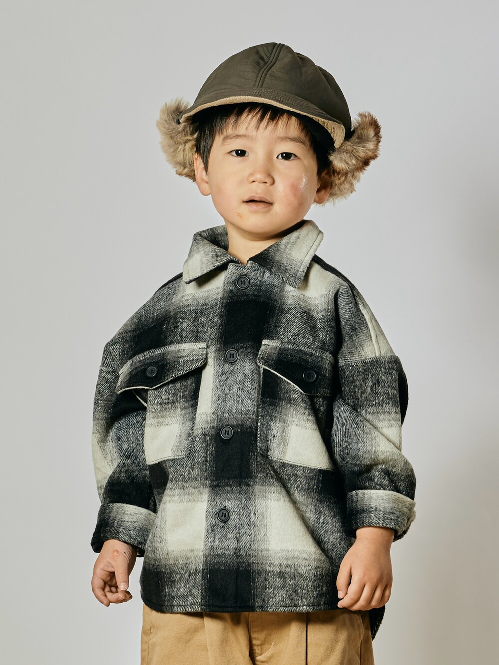 ベージュ系のチノパンツ、ブラック系のブルゾン、ベージュ系のブーツを着用したキッズの冬コーディネートの2枚目の写真