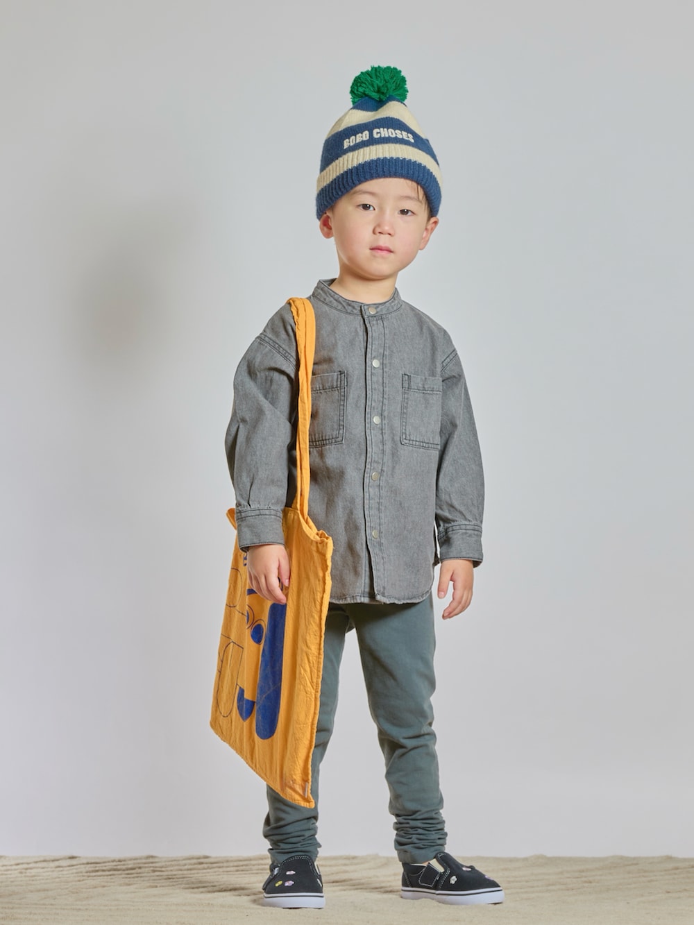 イエロー系のトートバッグ、ブラック系のシャツ/ブラウス、ブラック系のスリッポンを着用したキッズの秋コーディネートの2枚目の写真