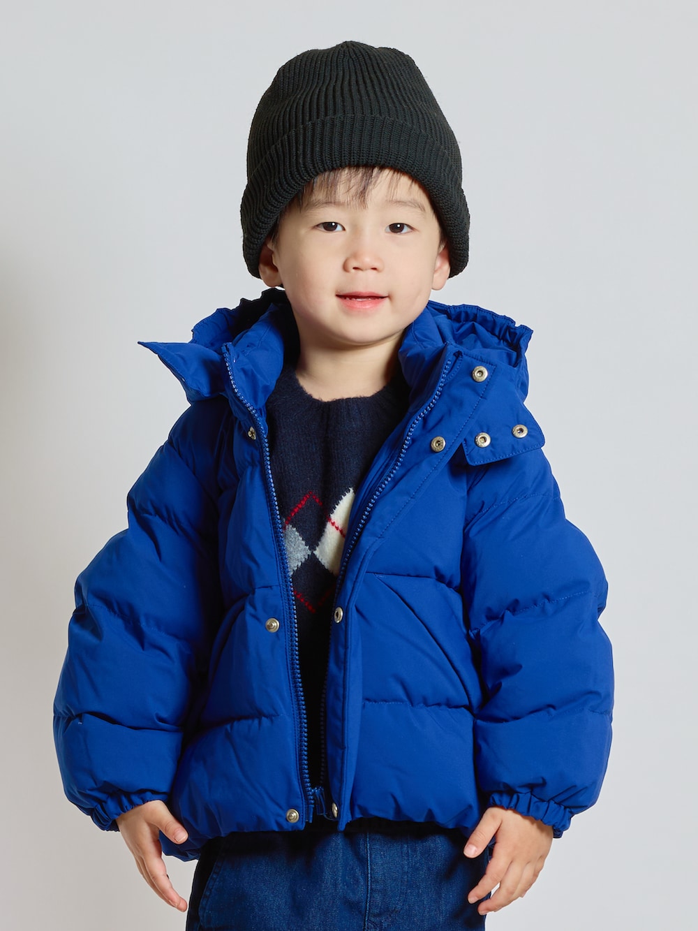 ブルー系のニット/セーター、ブルー系のダウンジャケット/コート、ブルー系のデニムパンツを着用したキッズの秋コーディネートの2枚目の写真