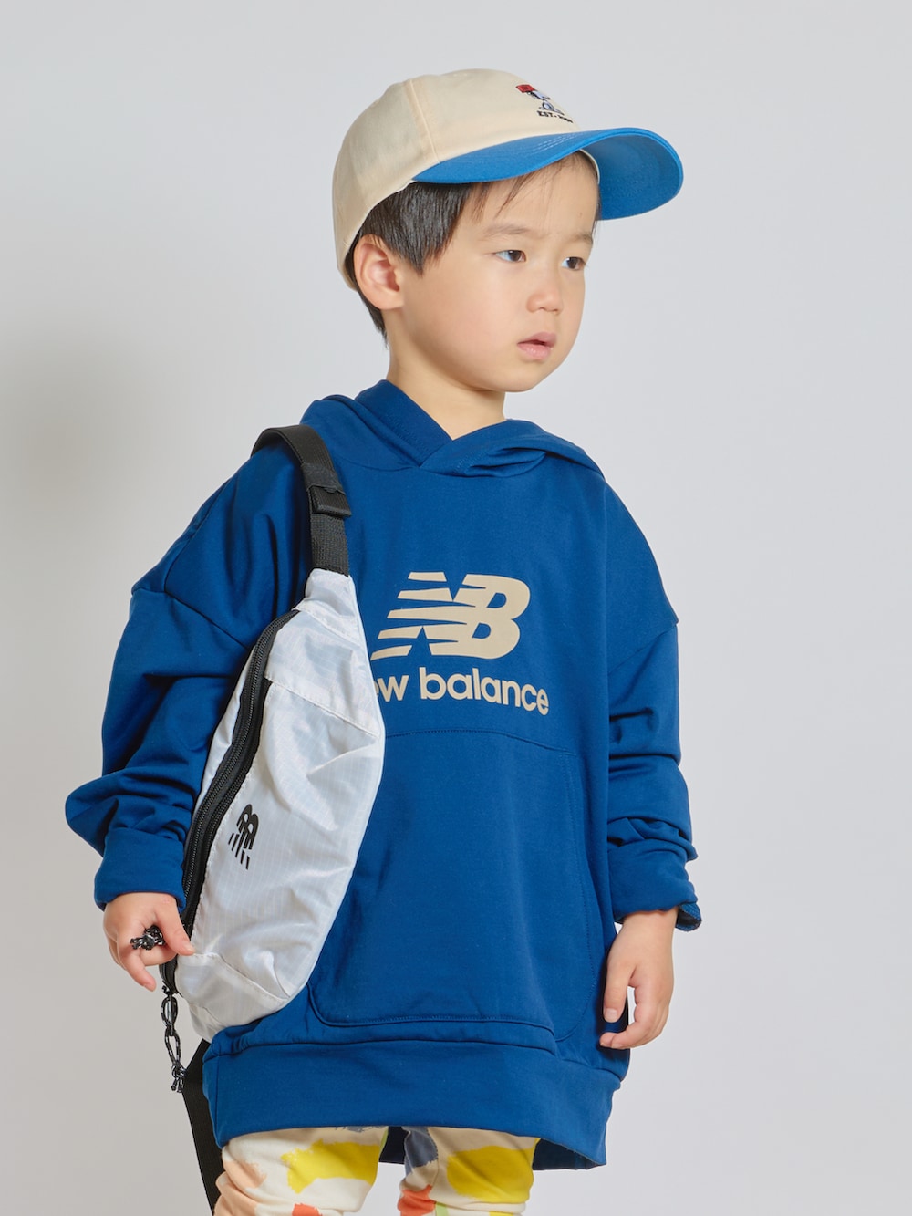 ブルー系のスウェット、ホワイト系のボディバッグ/ウエストポーチ、ホワイト系のスニーカーを着用したキッズの春コーディネートの2枚目の写真