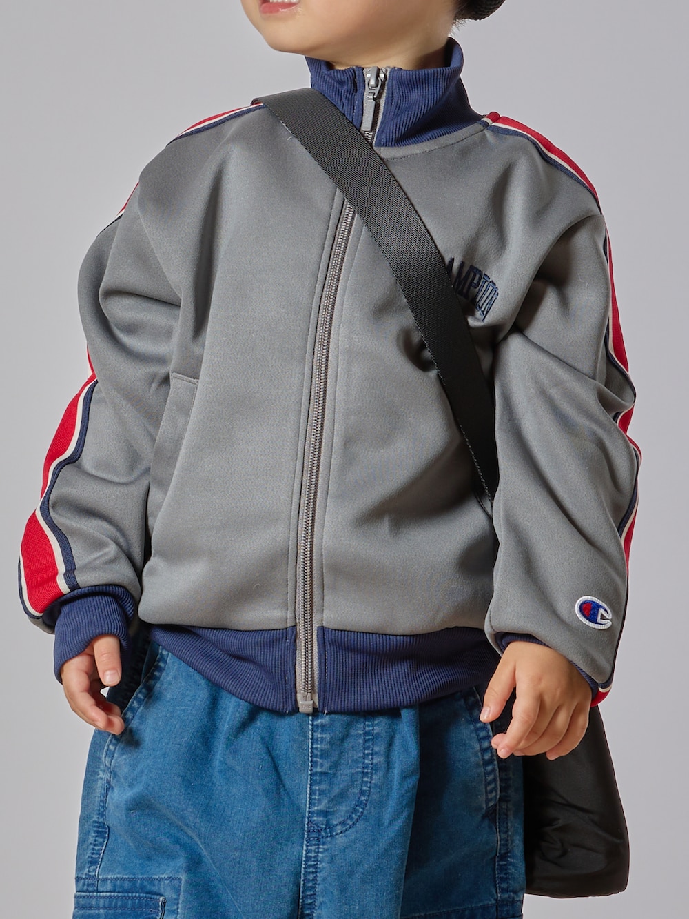 グレー系のブルゾン、ブルー系のカーゴパンツ、レッド系のスニーカーを着用したキッズの秋コーディネートの4枚目の写真