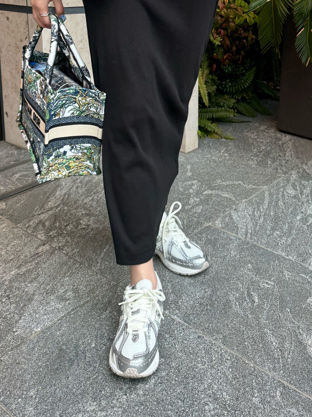 ブラック系のワンピース、ホワイト系のダウンジャケット/コート、シルバー系のスニーカーを着用したレディースの春コーディネートの4枚目の写真