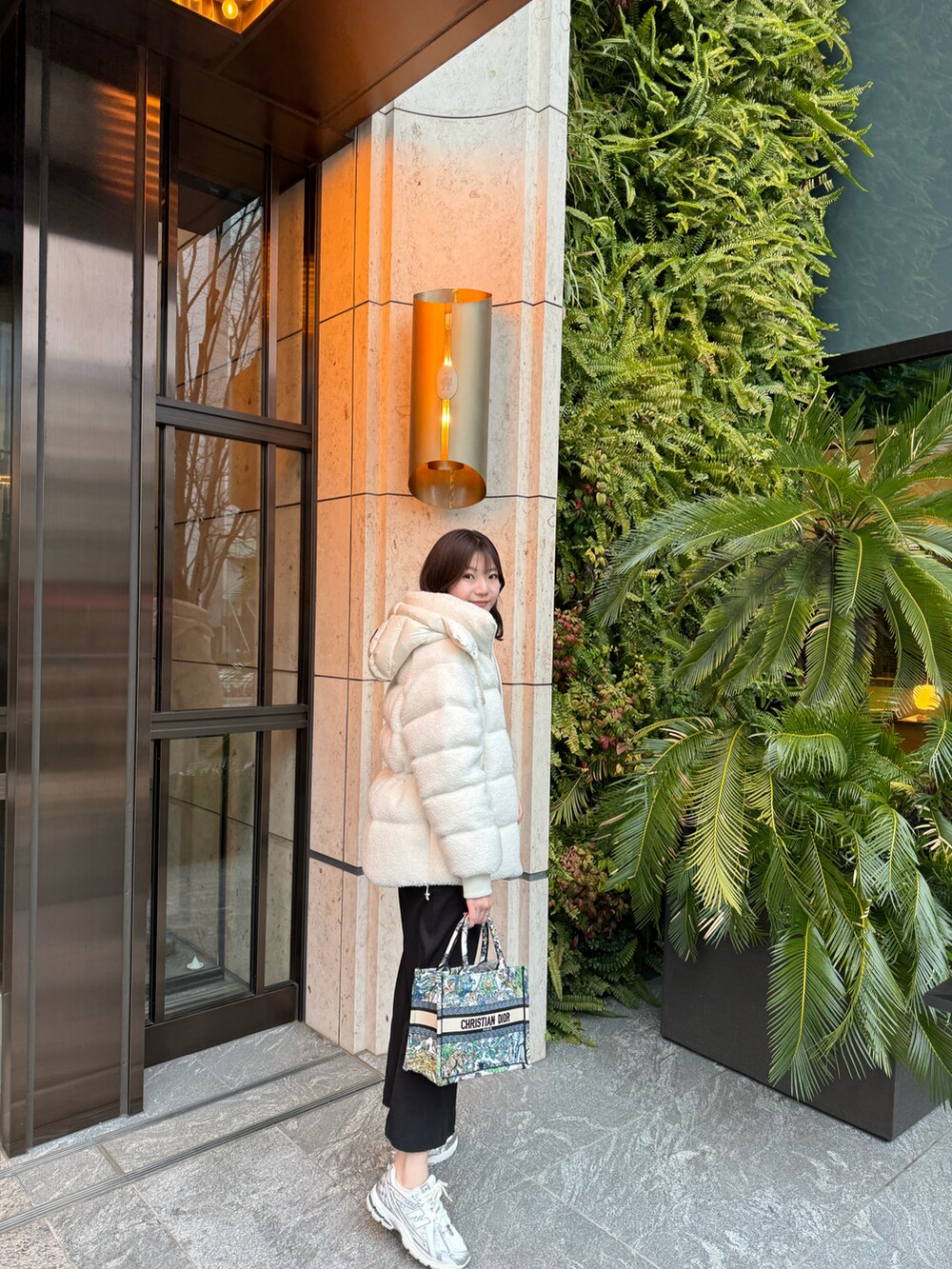 ブラック系のワンピース、ホワイト系のダウンジャケット/コート、シルバー系のスニーカーを着用したレディースの春コーディネートの2枚目の写真