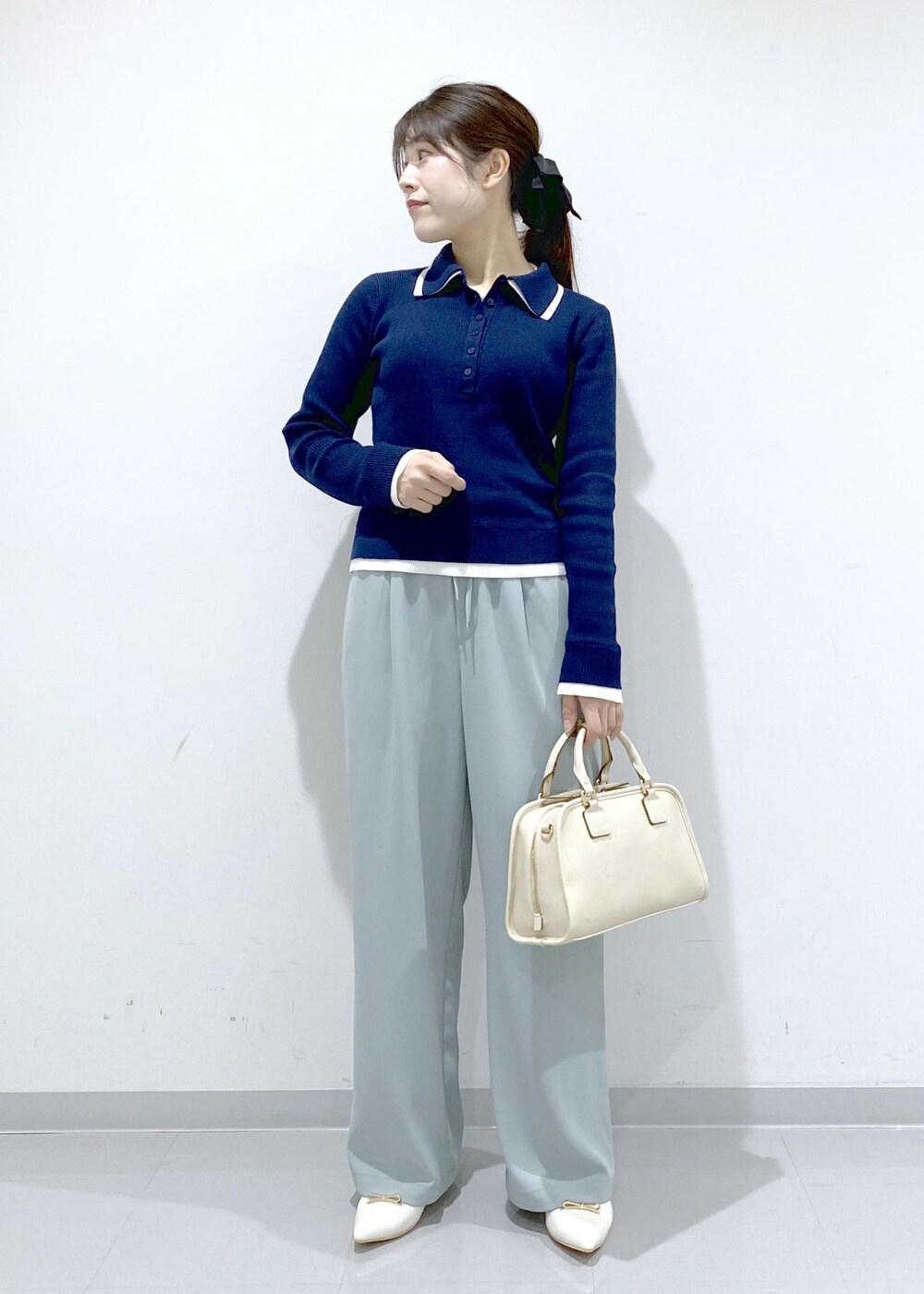 ホワイト系のボストンバッグ、ホワイト系のパンプス、ブルー系のニット/セーターを着用したレディースの冬コーディネートの8枚目の写真