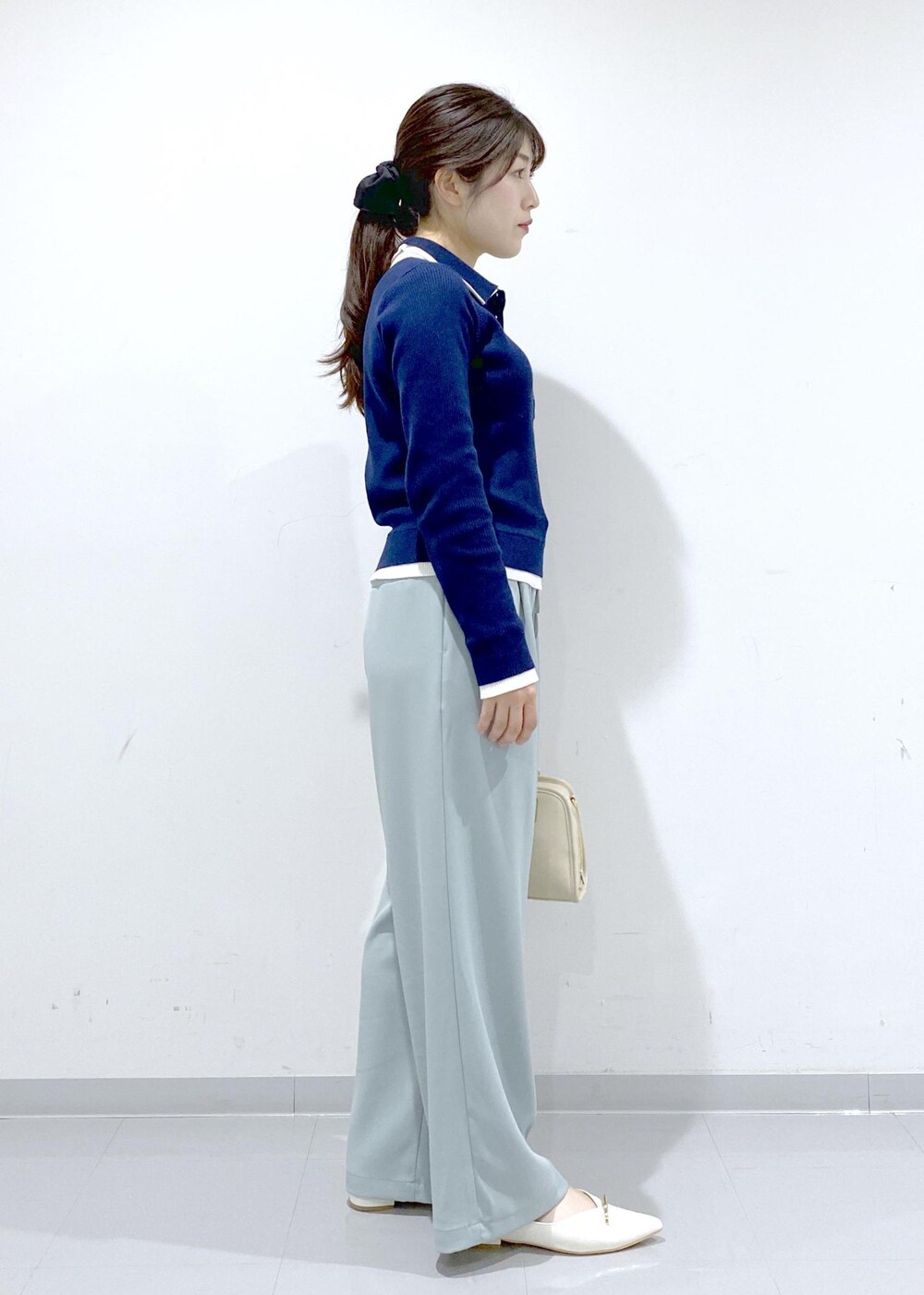 ホワイト系のボストンバッグ、ホワイト系のパンプス、ブルー系のニット/セーターを着用したレディースの冬コーディネートの6枚目の写真
