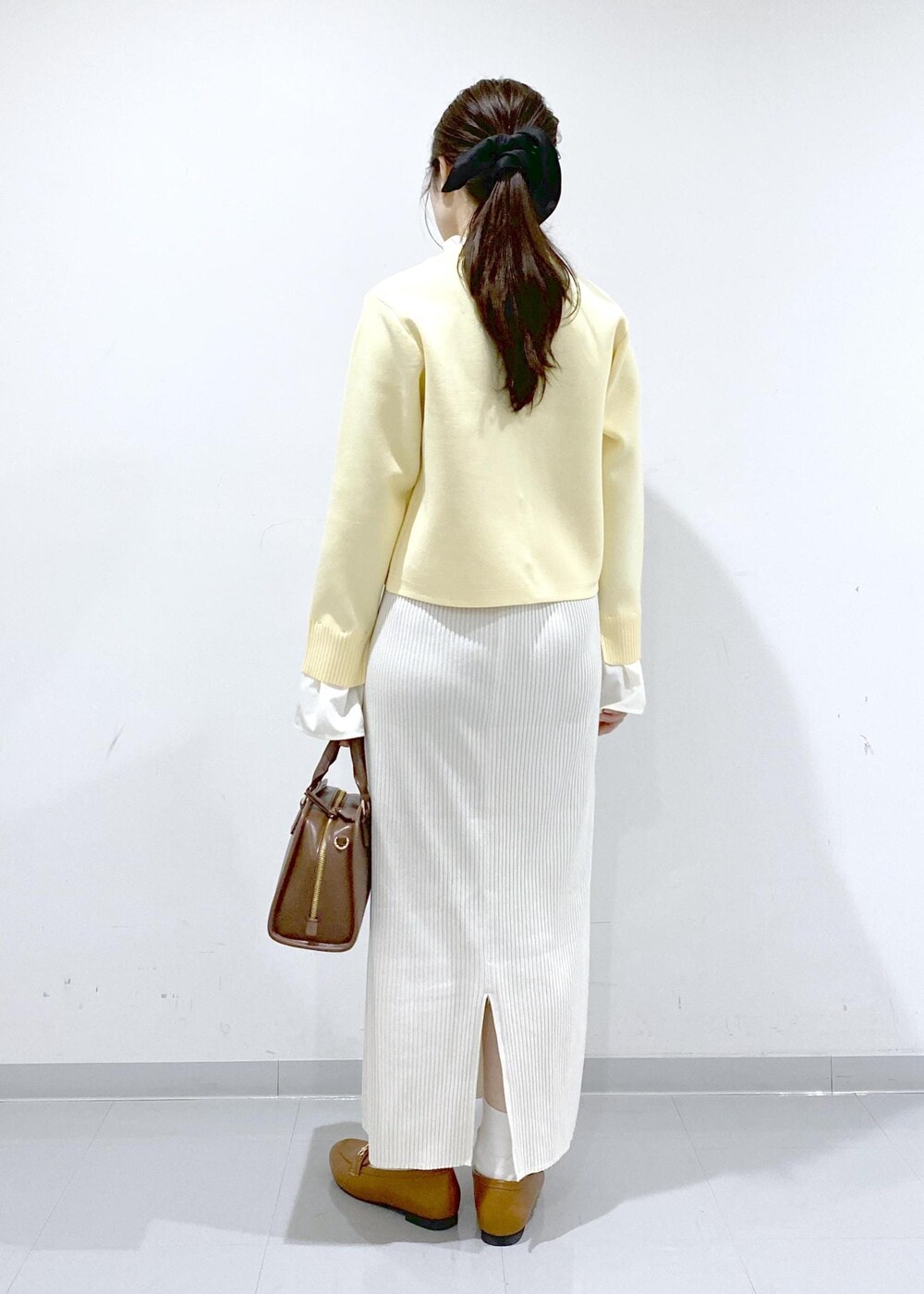 イエロー系のローファー、ブラウン系のボストンバッグ、ホワイト系のスカートを着用したレディースの冬コーディネートの5枚目の写真